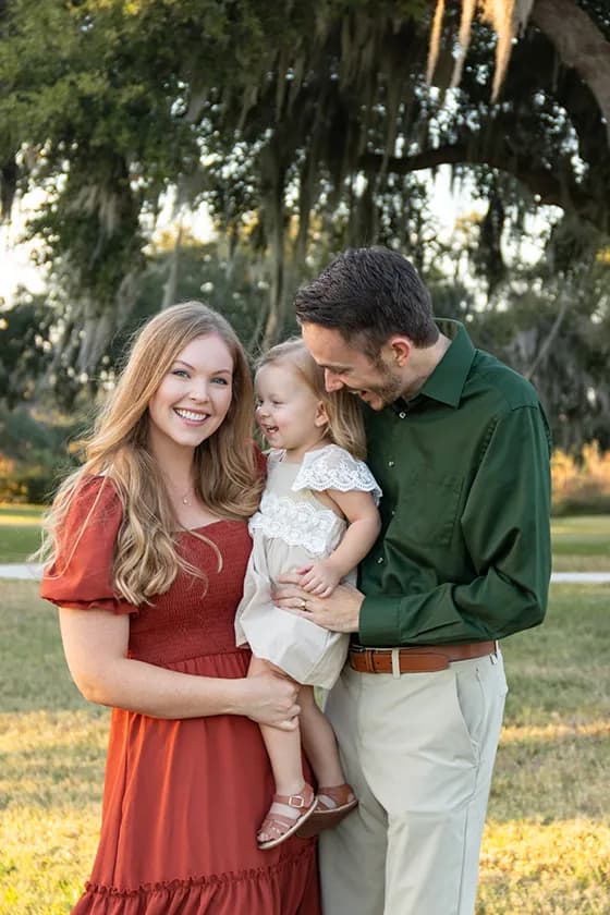 Dad smiling at young daughter that the mom is holding