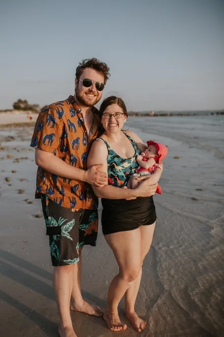 New parents hold newborn baby girl at the beach