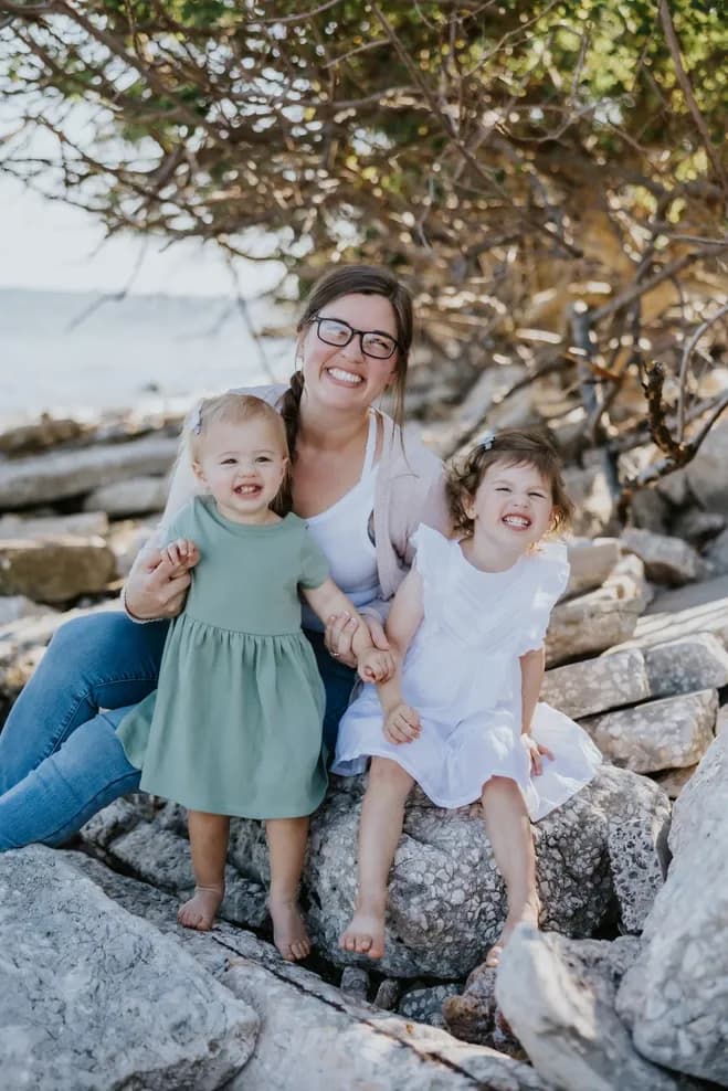 Image of mom sitting on rocks with her two young daughters